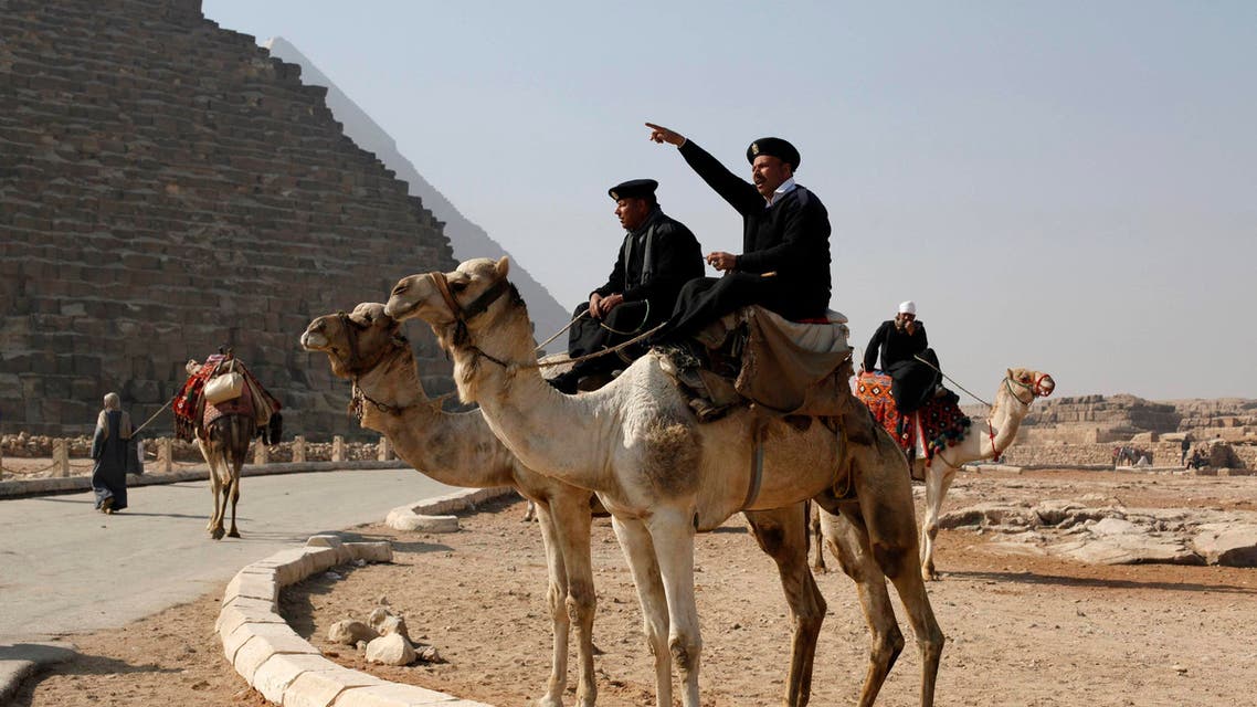 A police officer sitting on a camel talks to workers at the Giza pyramids, south of Cairo, Feb, 20, 2014. (Reuters)