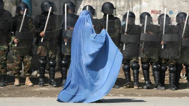 A woman wearing a burqa walks past riot police outside a gathering in Kabul. (File photo: Reuters) 