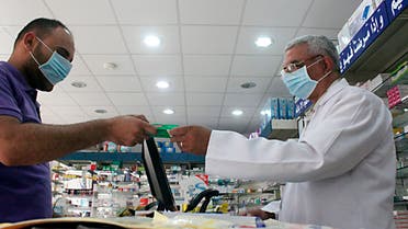 A man, wearing a surgical mask as a precautionary measure against the novel coronavirus, pays for medicine at a hospital pharmacy in Khobar city in Dammam May 21, 2013. reuters