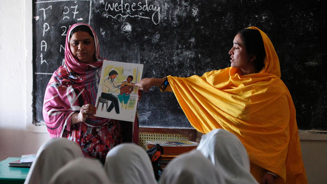 Teachers display a card with an illustration depicting a girl going through a medical checkup by a doctor, as they describe preventive measures to avoid when sexual harassment occurs. (Reuters)