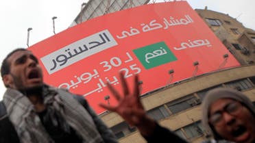 Pro-Mursi university students and supporters of the Muslim Brotherhood shout slogans in front of a billboard on the new constitution which reads "Participating in the constitution means 'Yes' to June 30 and January 25" at Tahrir Square in Cairo December 1, 2013. reuters