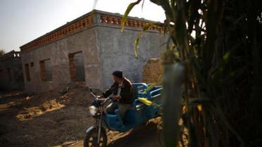 An ethnic Uighur man drives a tricycle near a construction site for new houses in Turpan, Xinjiang province Oct. 31, 2013. (Reuters)