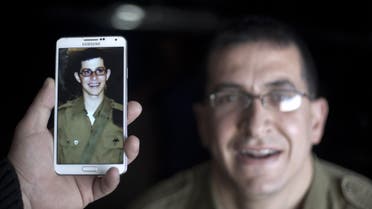 A staff holds a mobile phone to compare the image of Gilad Shalit to the likeness of actor Mahmoud Karira (background) during the shooting of a 90-minute film entitled "Fleeting Illusion" on February 27, 2014 in Gaza City. afp
