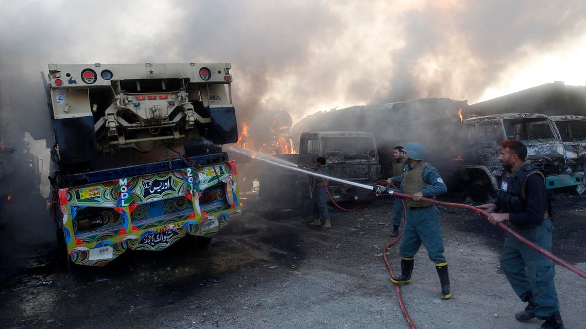 Afghan policemen extinguish burning NATO supply trucks after what police officials say was an attack by militants in the Torkham area near the Pakistani-Afghan border in Jalalabad Province December 18, 2013.