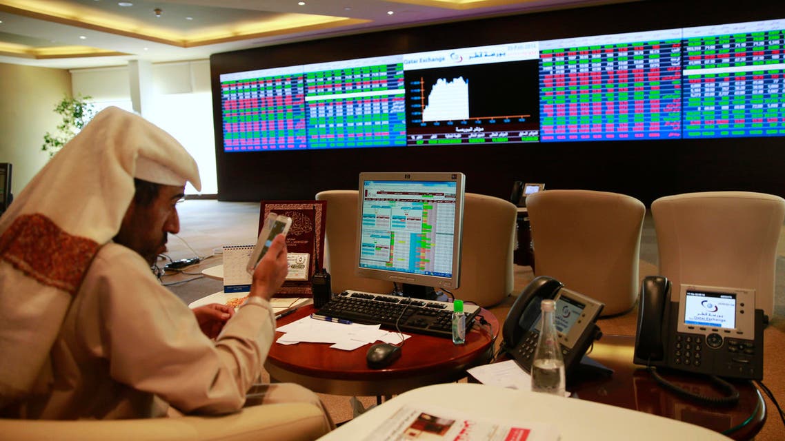 A trader uses his mobile phone behind his desk in front of the Qatar stock exchange board, in Doha February 4, 2014. (File photo: Reuters)