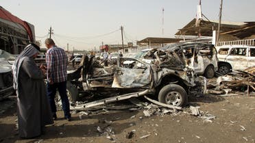  Iraqis stand near burnt out vehicles after a car bombing at an area of car dealerships on March 7, 2014. (AFP)