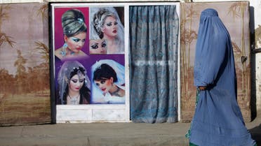An Afghan woman in a burqa walks past a beauty saloon shop in Kabul September 11, 2013. 