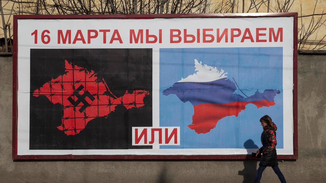 A woman walking by a poster calling people to vote in the upcoming referendum, in the Crimean port city of Sevastopol March 10, 2014. reut