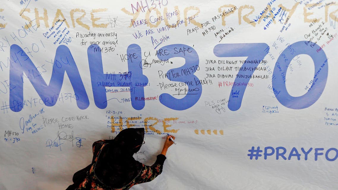 A woman writes a message of support and hope for the passengers of the missing Malaysia Airlines MH370 on a banner at Kuala Lumpur International Airport March 12, 2014. (Reuters)