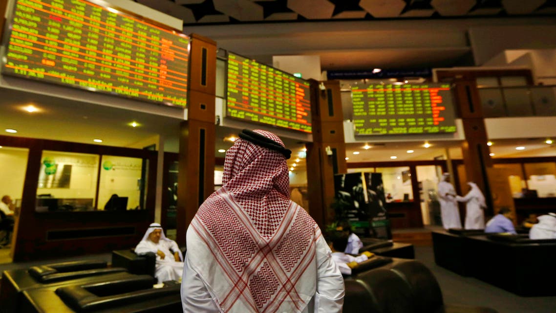 An investor looks up at screens displaying stock information at the Dubai Financial Market, June 17, 2013. (Reuters)