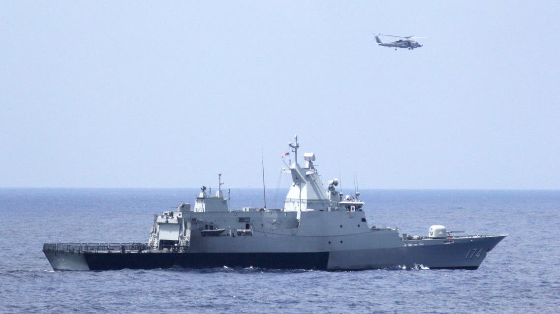 A Malaysian navy warship and a U.S. Navy helicopter conduct a coordinated air and sea search for a missing Malaysian Airlines jet in the Gulf of Thailand March 12, 2014. (Reuters)