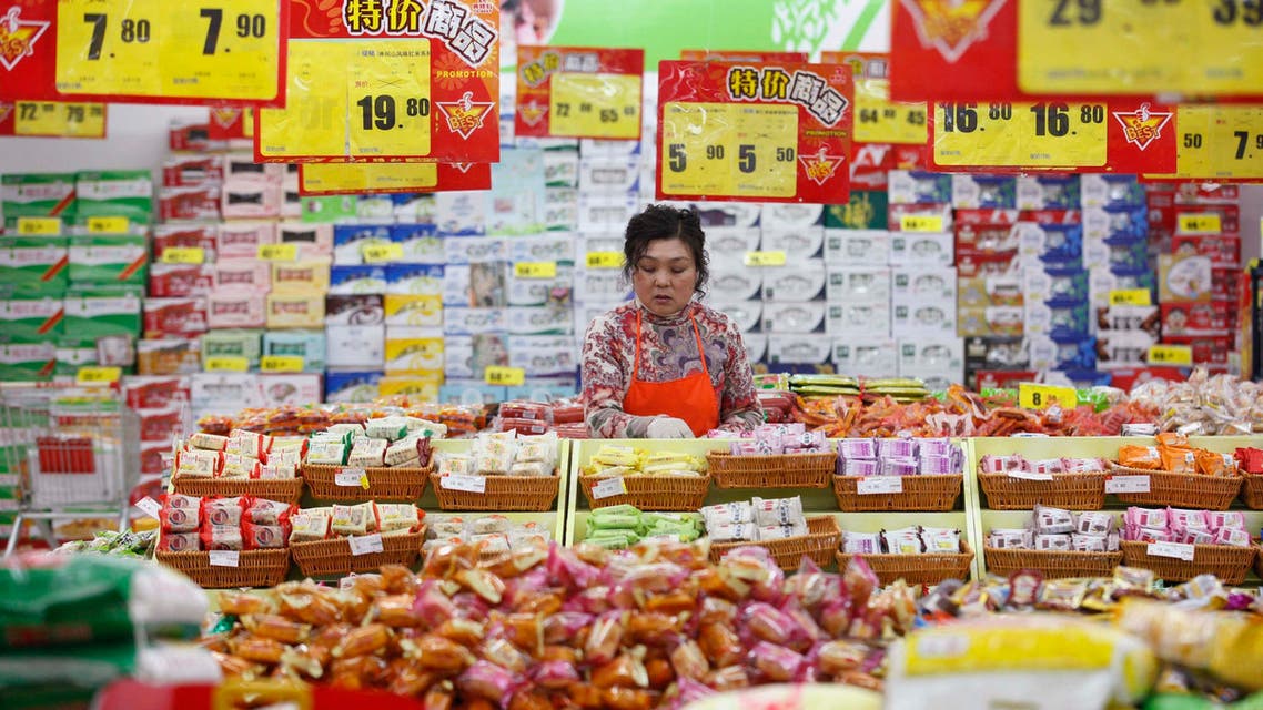 An employee arranges stock under price tags at a supermarket in Huaibei, Anhui province in China, March 9, 2014.