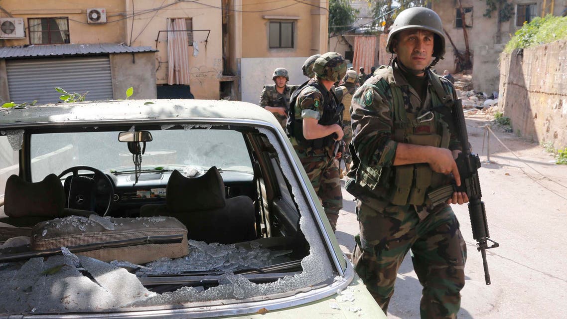 Lebanese Army soldiers walk past a damaged car as they are deployed after clashes in south Beirut March 23, 2014. reuters