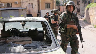 Lebanese Army soldiers walk past a damaged car as they are deployed after clashes in south Beirut March 23, 2014. reuters