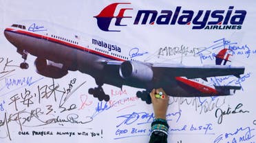 A woman writes a message on a board for passengers onboard missing Malaysia Airlines Flight MH370 and their family members, in Kuala Lumpur on March 22, 2014. (Reuters)