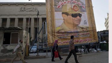 Egyptian walk past a huge poster of Egypt's former Defense Minister and armed forces chief General Abdul Fatah el-Sisi outside the High Court in downtown Cairo, on March 27, 2014. (AFP)