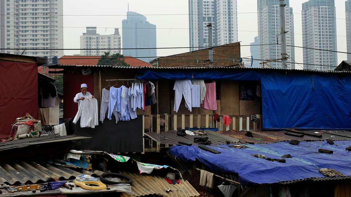 A man with a cigarette in his mouth, hangs out a shirt to dry on the second floor of a house near the business district in Jakarta. (File photo: Reuters)