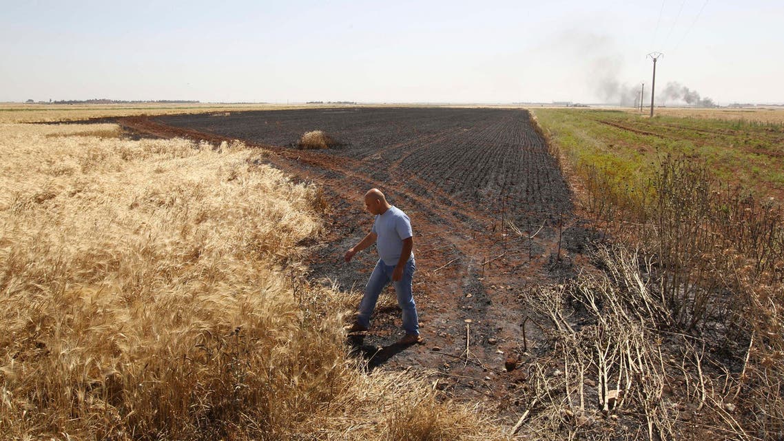A man inspects an area of a burned wheat field which activists said was caused by shelling by the Syrian regime in Aleppo's countryside June 1, 2013. reuters