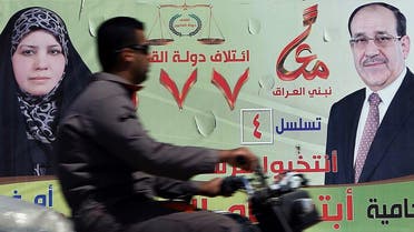 A man rides his motor bike past a large election campaign banner showing Iraqi Prime Minister Nuri al-Maliki (R) along a street in the central Shiite Muslim shrine city of Karbala, on April 6, 2014. (AFP)
