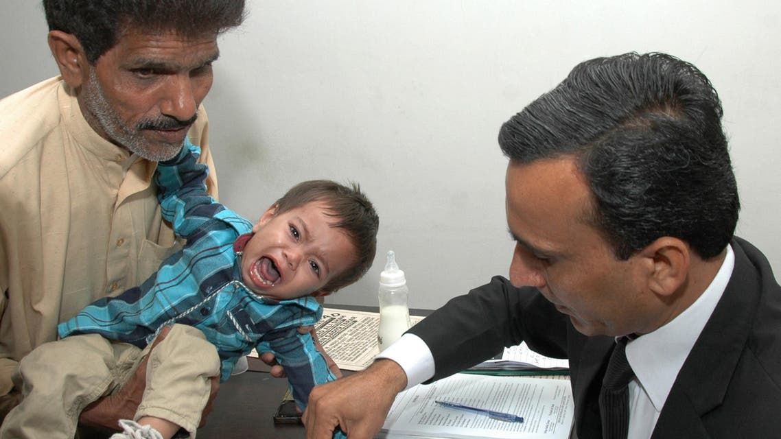 This photograph taken on April 3, 2014 shows a Pakistani lawyer taking the thumb impression from nine-month-old toddler Mohammad Musa on a bail bond in Lahore. (AFP)