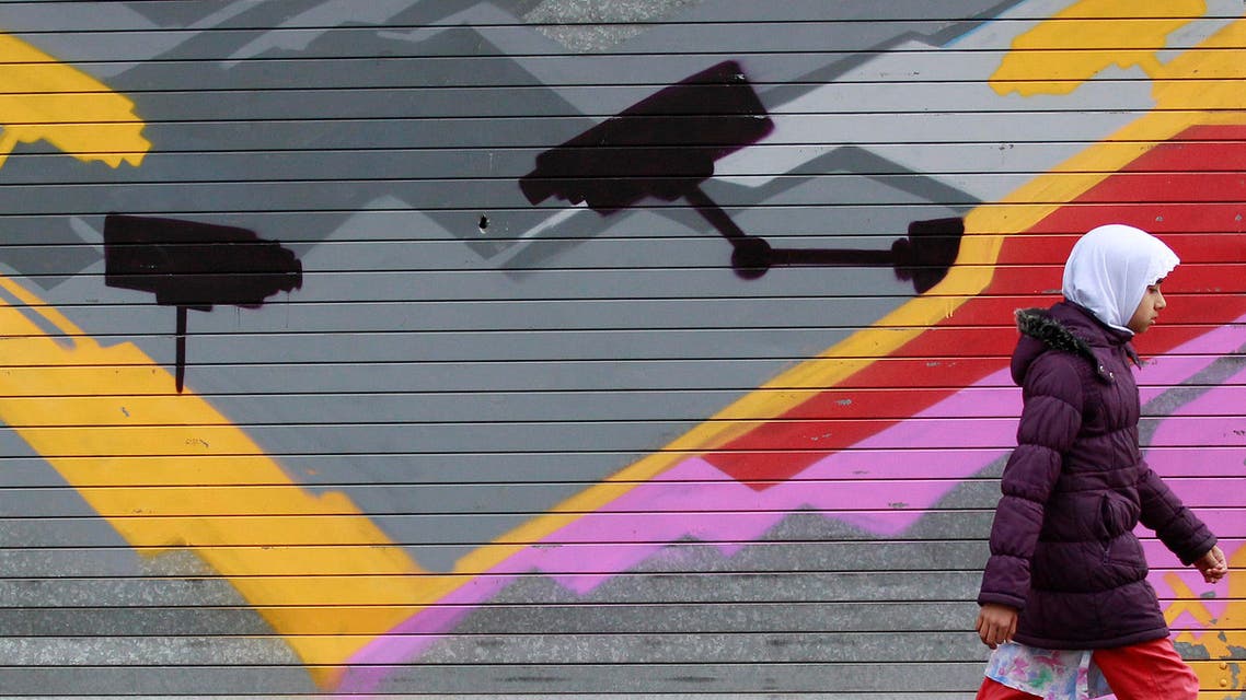 A girl walks past graffiti showing CCTV cameras in the Sparkbrook area of Birmingham, central England, Oct. 2, 2010. (Reuters)