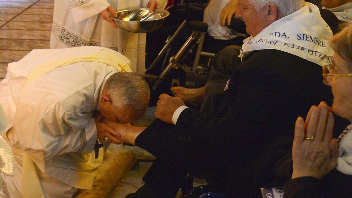 Pope Francis (L) kisses the foot of a man as he performs a traditional ceremony as part of the Holy Week on April 17, 2014 in Rome. (AFP)