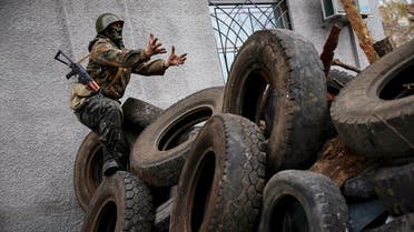 An armed man gestures from a barricade in front of the police headquarters in Slaviansk April 12, 2014. reuters