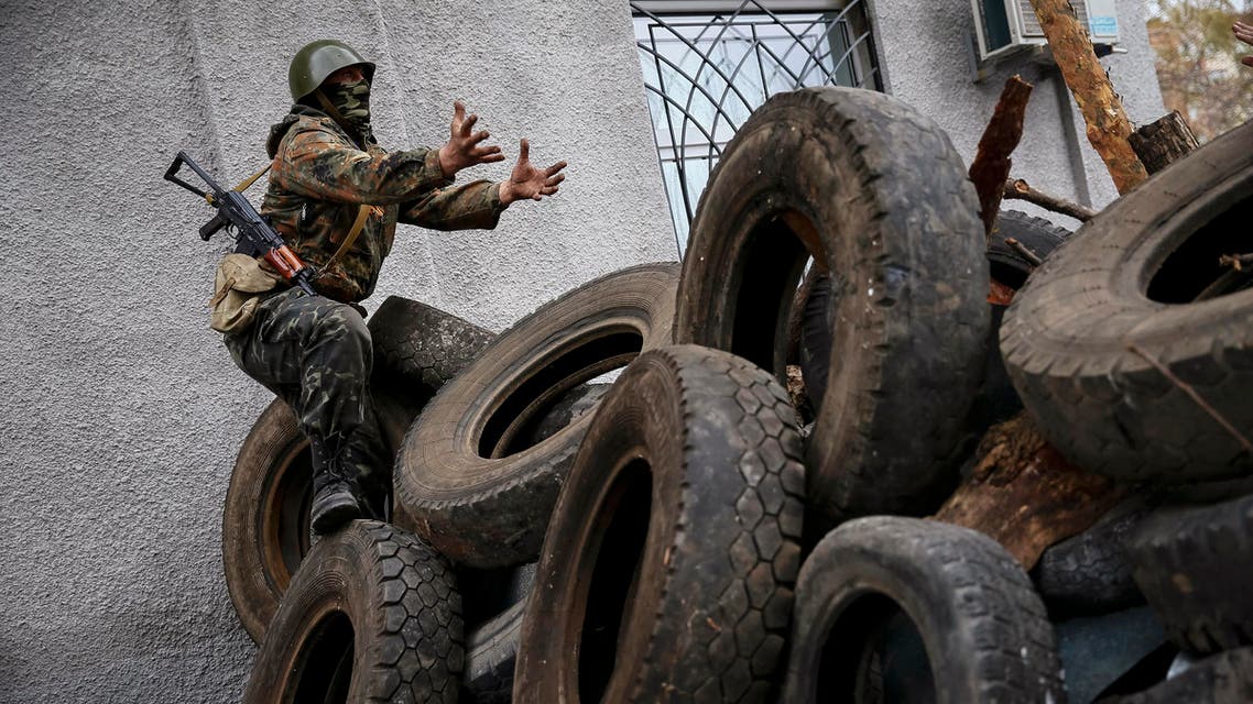 An armed man gestures from a barricade in front of the police headquarters in Slaviansk April 12, 2014. reuters