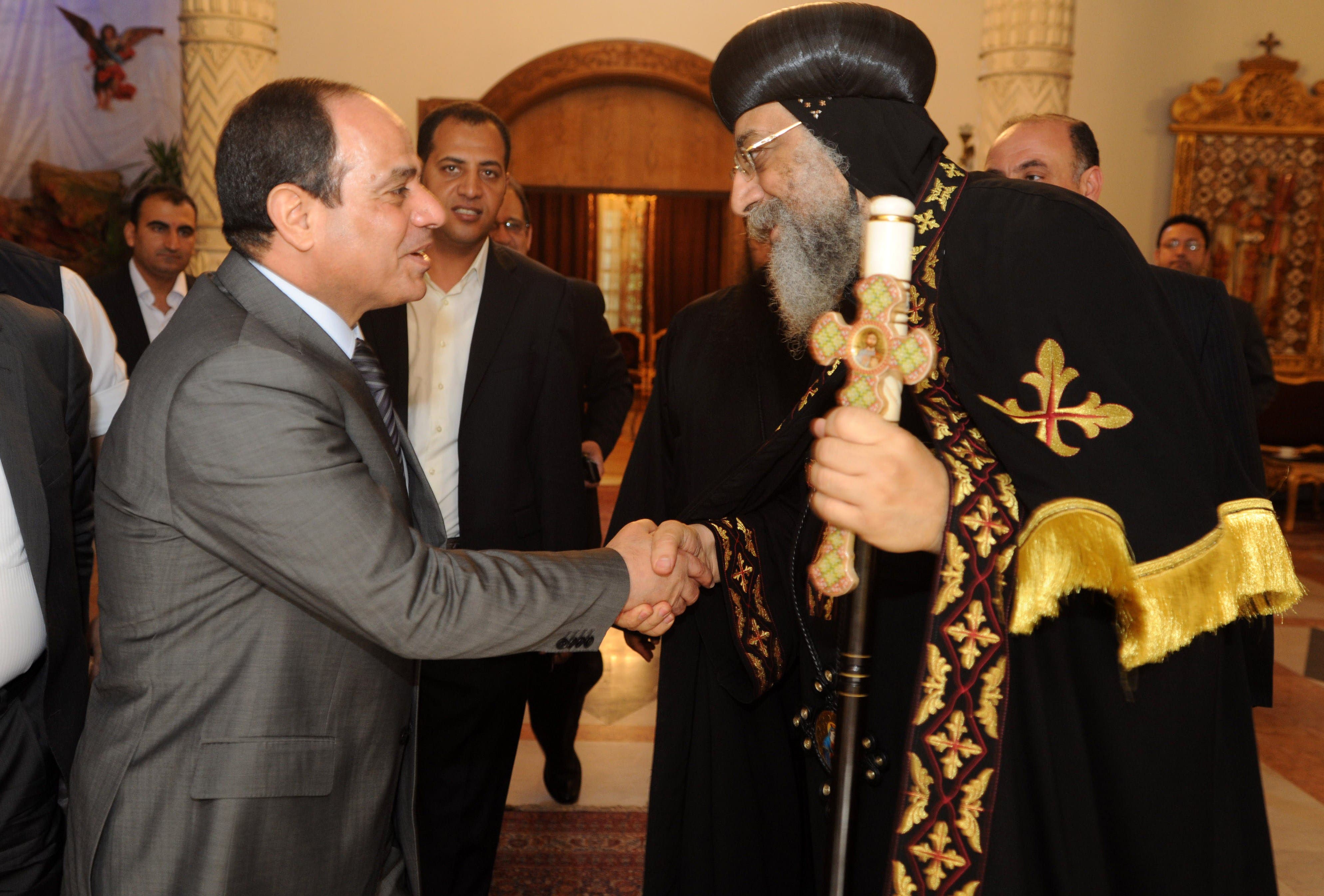 A handout picture released by the press office of Abbasiya Cathedral shows Egyptian former Defence Minister and armed forces chief General Abdul Fatah al-Sisi (L) shaking hands with Pope Tawadros II, pope of Egypt's Coptic Orthodox Church on April 19, 2014 during a visit at Cathedral of Abbasiya in Cairo. (AFP)