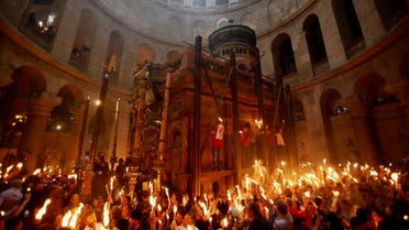 Christian Orthodox worshippers hold up candles lit from the 'Holy Fire' as thousands gather in the Church of the Holy Sepulchre in Jerusalem's old city on April 19, 2014 during the 'Holy Fire' ceremony on the eve of the Orthodox Easter. AFP