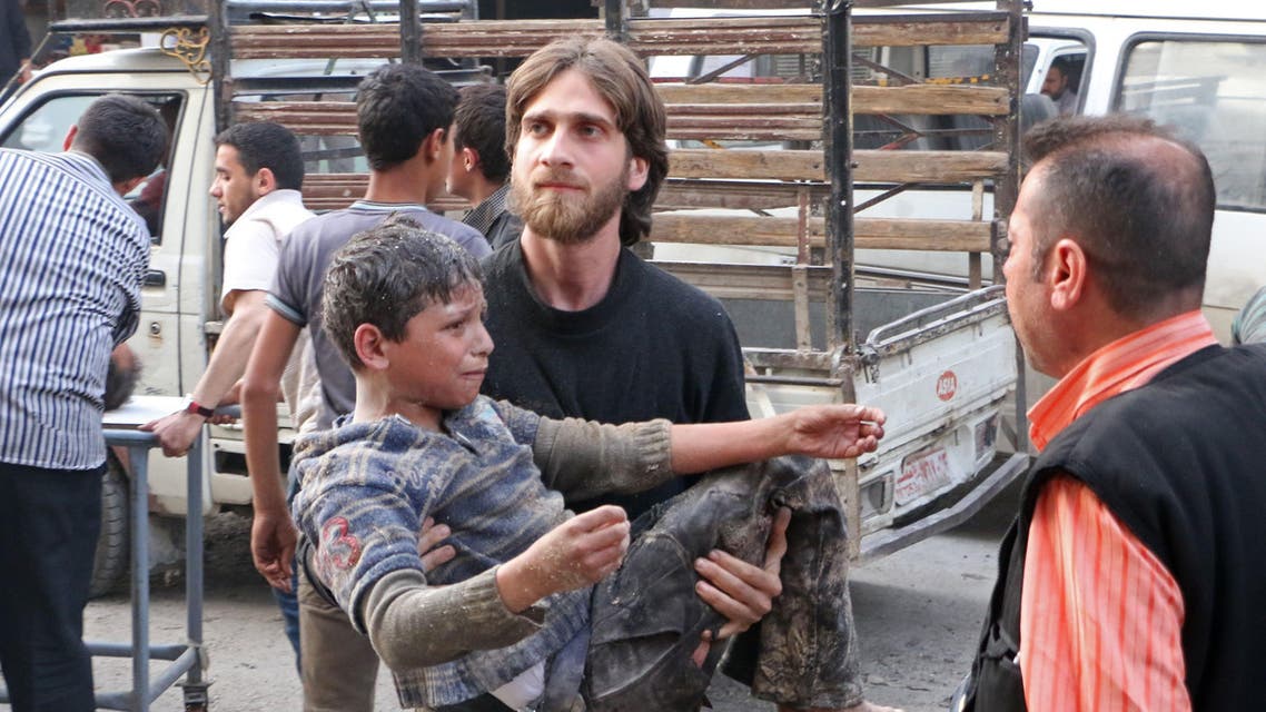 A rebel fighter carries a wounded child following a reported air strike by pro-regime forces on the village of Atareb in the northern Syrian province of Aleppo, on April 24, 2014. AFP