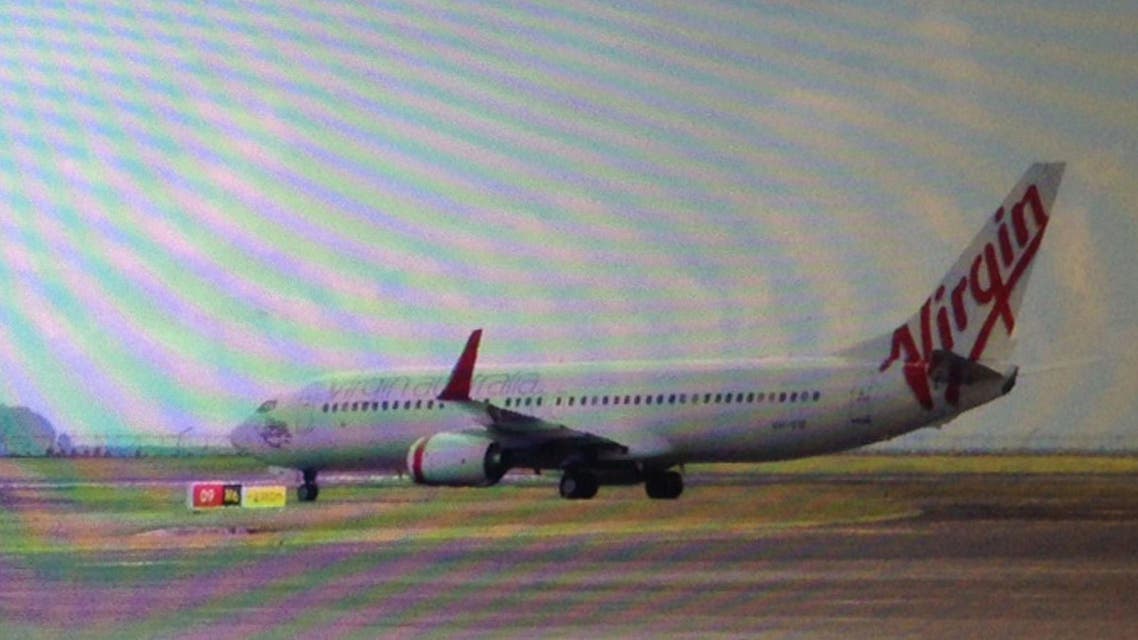 This photo taken through the window of a plane shows a Virgin Australia plane at the centre of a hijacking scare sitting on the tarmac at Bali airport in Denpasar on April 25, 2014. (AFP)