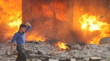 A man walks past a burning building following a reported air strike by pro-regime forces on the northern Syrian city of Aleppo, on April 24, 2014. (AFP)