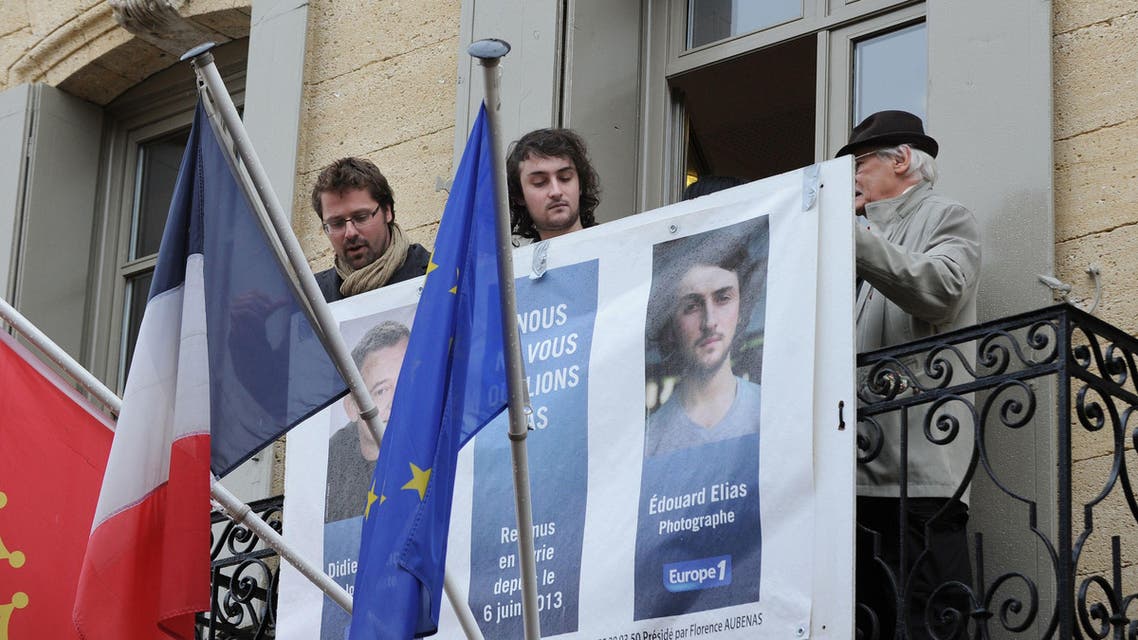 French photographer Edouard Elias (C), who was taken hostage north of the main northern Syrian city of Aleppo on June 6, 2013, removes his portrait from the balcony of the city hall upon his return to his native village of Saint Quentin La Poterie, southern France, where residents welcomed him. AFP