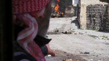 A Free Syrian Army fighter points to a burning tank in Daraa