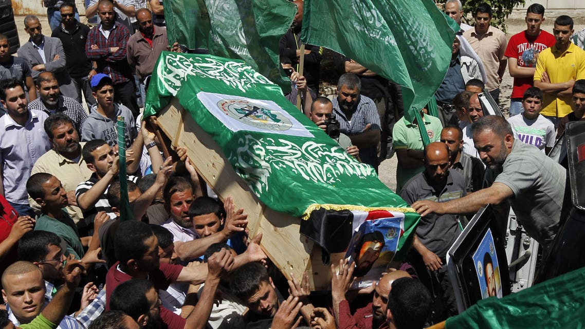 Palestinian mourners wave the green flag of the Islamist movement Hamas as they attend the funeral of two Hamas members who were killed in 1998, Adel and Imad Awadallah, in the West Bank city of Ramallah on April 30, 2014. (AFP)