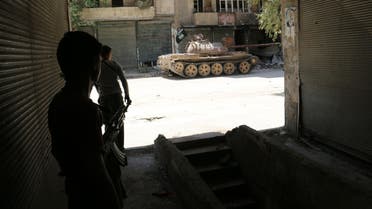 Opposition fighters take cover as a tank belonging to their forces is seen in a street of the Syrian city of Aleppo on April 17, 2014. AFP