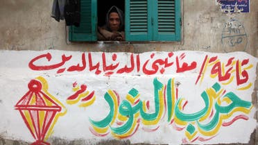 A woman looks through her window above an electoral slogan for Salafi political party Al-Nour that reads, "Together hand in hand we build the country through religion." Reuters