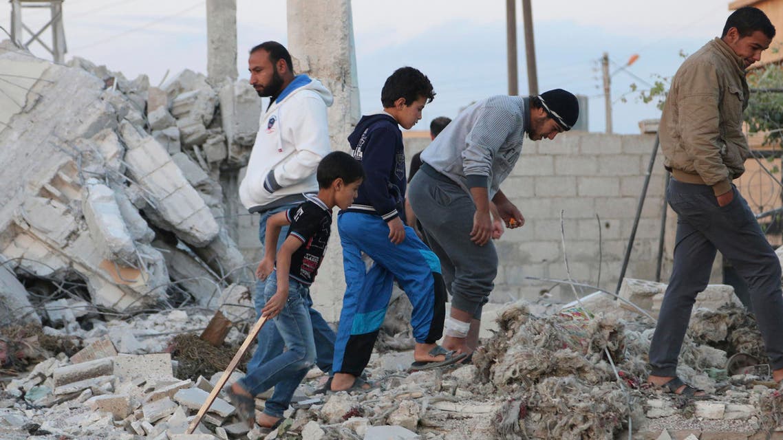 People walk on rubble of collapsed buildings at a site hit by what activists say was a barrel bomb dropped by forces loyal to Syria's President Bashar al-Assad at al-Musayfra in Daraa province May 13, 2014. (Reuters)
