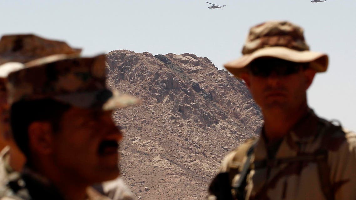 Kobra helicopters fly behind a U.S. and a Jordanian soldier during the Eager Lion military exercise near the southern town of Al Quweira, 50 km from the coastal city of Aqaba June 19, 2013. reuters