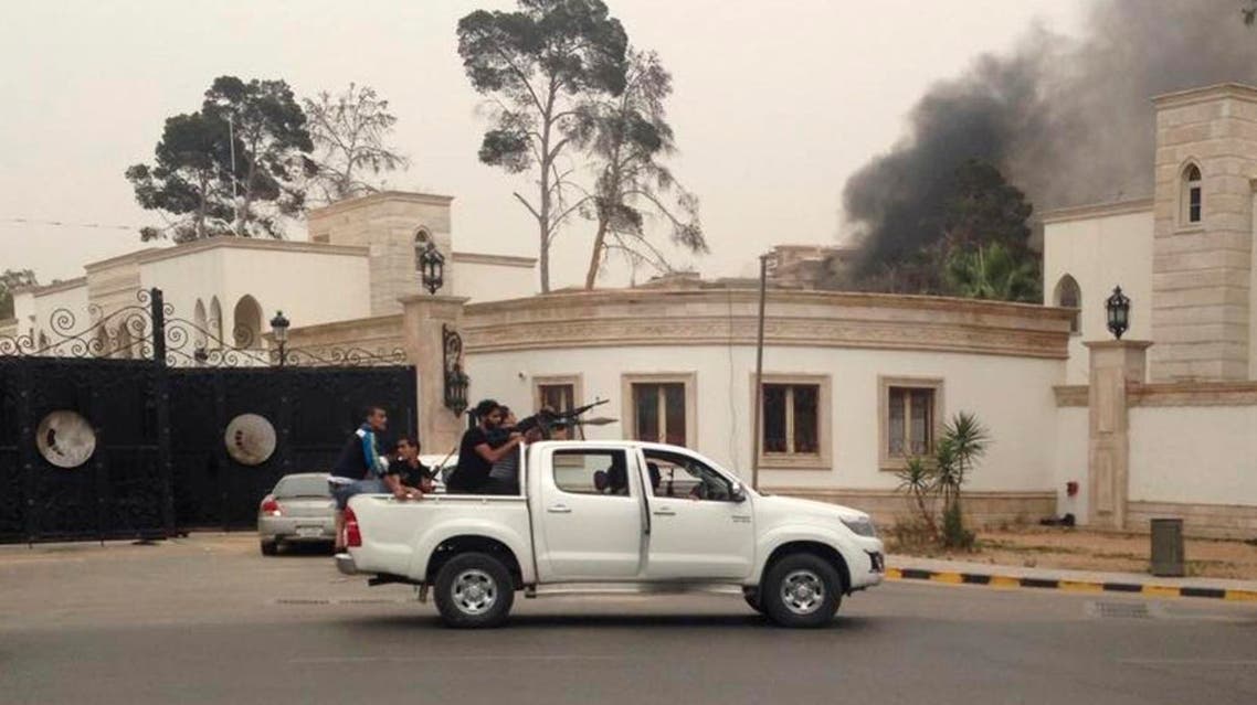 Armed men aim their weapons from a vehicle as smoke rises in the background near the General National Congress in Tripoli May 18, 2014. reuters