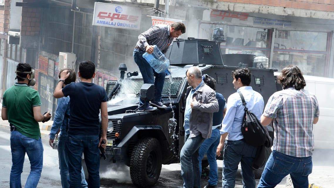 A man pours water on an armoured police vehicle after it was set on fire by fire bombs during clashes between protesters and riot police in Istanbul May 22, 2014. reuters