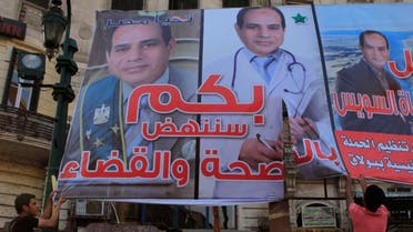 Members of the "April 6" and "Against you" movement with liberal activists cut a poster of presidential candidate and former army chief Abdel Fattah al-Sisi during a protest against him and a law restricting demonstrations as well as the crackdown on activists, in downtown Cairo May 24, 2014. Egyptians vote this week in an election expected to make former army chief Abdel Fattah al-Sisi president, marking a revival of strongman rule three years after the downfall of Hosni Mubarak. REUTERS