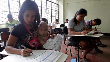 A mother with her daughter fills-up a ballot form together with other voters inside a precinct poll at a school in Manila May 13, 2013. (Reuters)