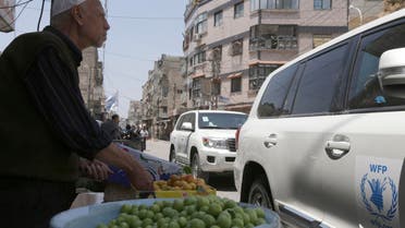 A fruit vendor stands beside passing World Food Program vehicles in eastern Ghouta of Damascus, May 24, 2014. (Reuters)