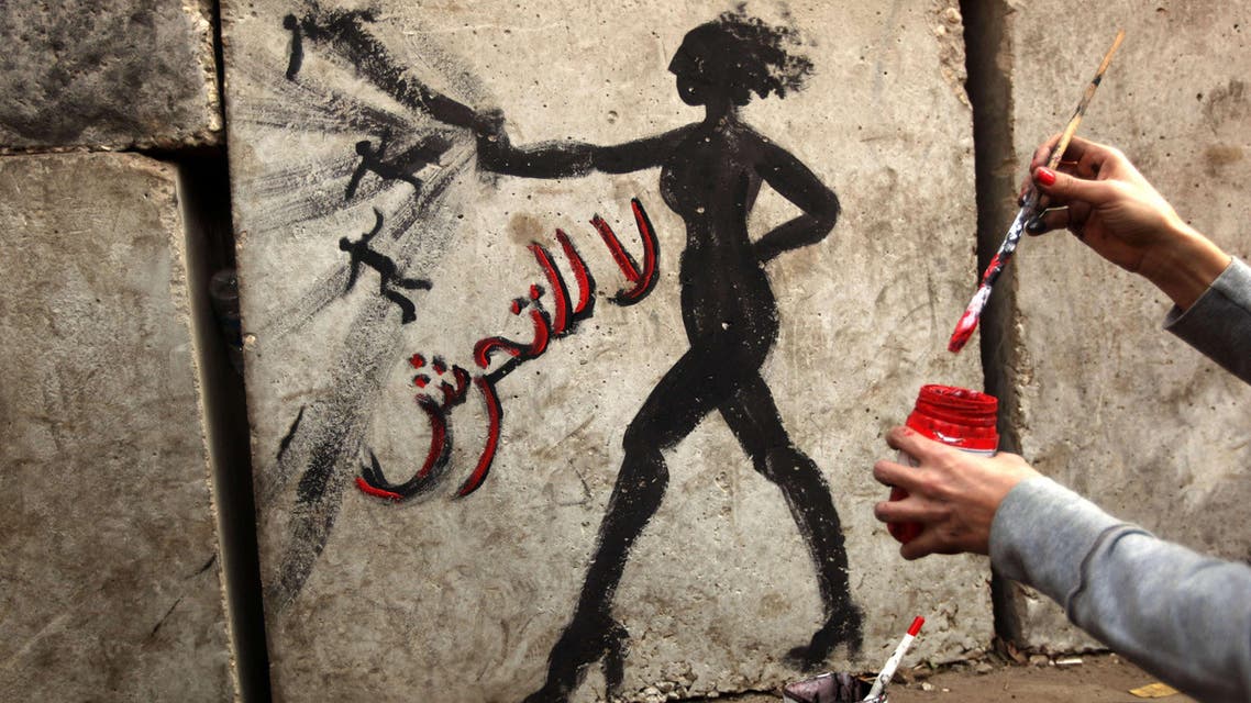 Egyptian activist drawing graffiti depicting a woman and reading in Arabic: "No to Sexual Harassement" afp