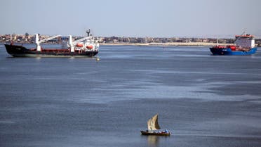 A fisherman travels on a boat front of container ships in the Suez canal near Ismailia port city, northeast of Cairo May 2, 2014. (Reuters)