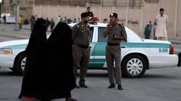 Women walk past members of Saudi security forces as they keep guard in Manfouha, southern Riyadh, November 14, 2013.