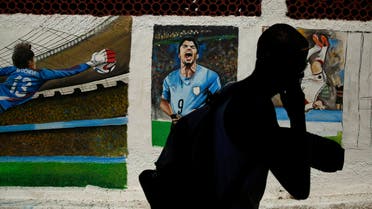 A man walks past murals of Mexico's goalkeeper Guillermo Ochoa and Uruguay's Luis Suarez on the Copacabana beach in Rio de Janeiro, June 27, 2014. (Reuters)