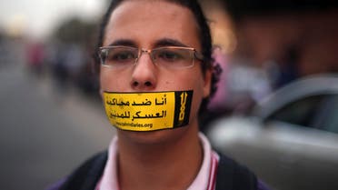 A demonstrator looks on with a sign reading "I am against the military courts for civilians" taped over his mouth during a human chain by members of the April 6 movement and liberal activists against the protest law. (Reuters)